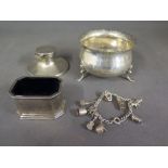 A silver hallmarked inkwell, sugar bowl with hallmark, a silver charm bracelet and a silver mustard