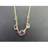 A 9ct gold oval amethyst necklace - The graduated collets to the fancy-link chain - Hallmarked