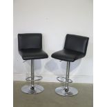 A pair of black faux leather hydraulic stools