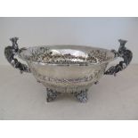 A large silver hallmarked bowl with twin griffin handles decorated with embossed foliate design