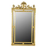 A French giltwood wall mirror in Louis XVI style, the rectangular central plate flanked by