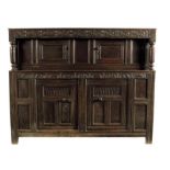 An early 18th century oak press cupboard, with a leaf carved frieze above a pair of panelled