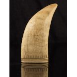 λ A scrimshaw whales tooth, decorated with a three masted sailing ship and with an urn of flowers,