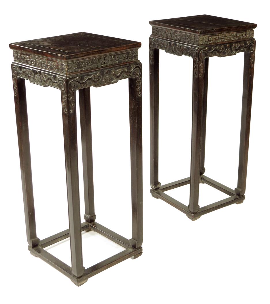 A pair of Chinese hardwood jardinière stands, each with a panelled top above a carved frieze