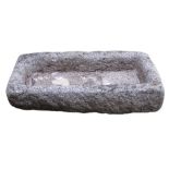 Two granite troughs, one broken into three pieces, both pierced with holes, 23cm high 93cm wide,