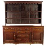 A George III oak dresser, the raised plate rack with a wavy edge frieze and with three shelves,