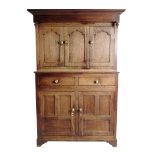 A George III Welsh oak press cupboard, with turn pendant finials above three ogee panelled doors,