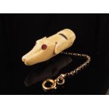 λ A Victorian ivory and ebony dog whistle, carved in the form of a greyhound's head with red stone