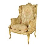 A Louis XV style giltwood bergère, the moulded frame carved with rocaille scrolls and leaves, late