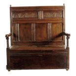 An oak settle, the panelled back carved with foliate lunettes above a twin hinged box seat, with