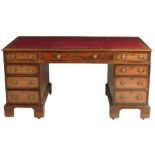 A mahogany twin pedestal desk, the gilt tooled red leather writing surface above an arrangement of