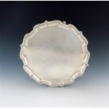 A silver salver, by Mappin and Webb, Sheffield 1956, circular form, moulded border, on three hoof