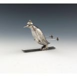 A modern Spanish novelty silver penguin on skis, the penguin with a woolly hat and holding ski