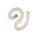 A three~row cultured pearl necklace, with a ruby~set white gold flower~head clasp. 50cm longest.