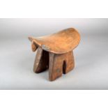 A Dinka stool, with end lifts, on split twin supports, the sides with pricked decoration, 19cm