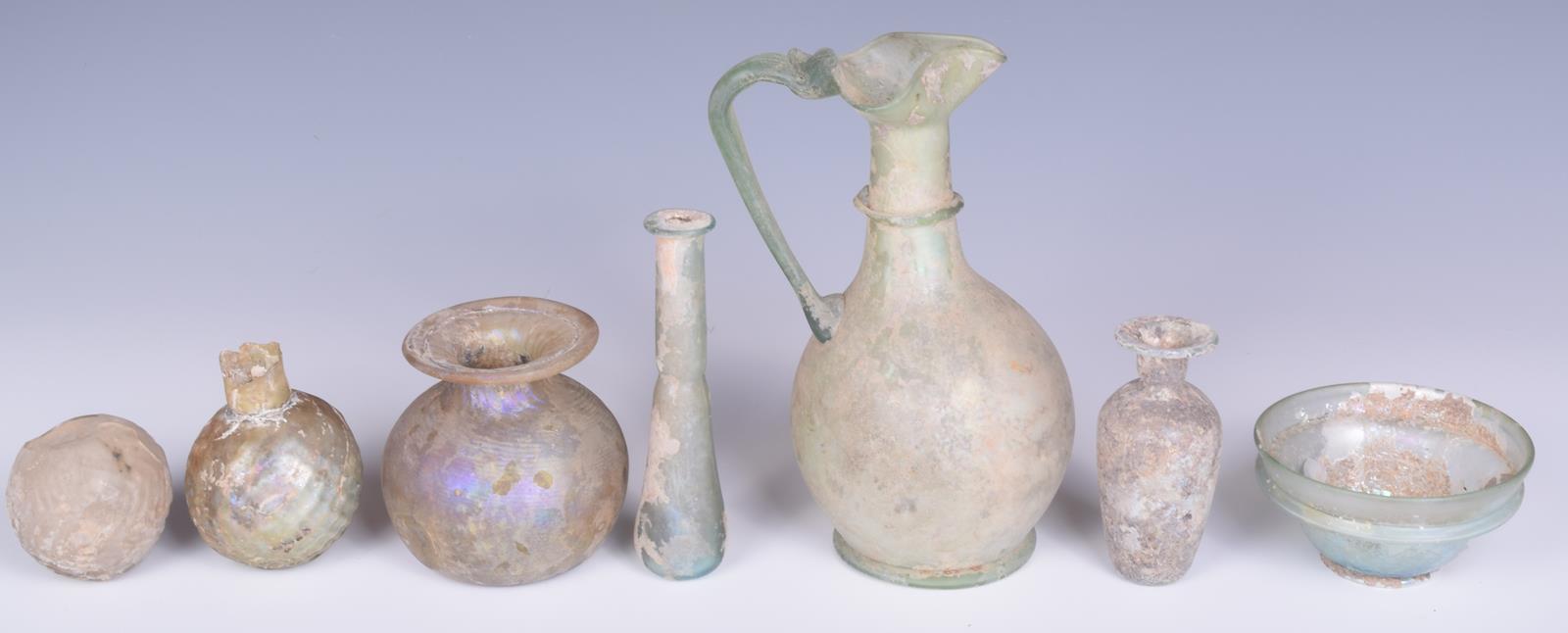 A Roman green glass jug, with a pinched spout and loop handle, 17cm high, a turquoise glass - Image 4 of 4