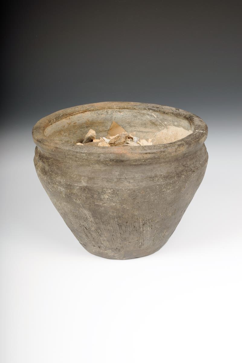 A bronze age earthenware cremation urn, with incised linear decoration to the sides, 15cm high,