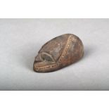 A Vanuatu carved stone amulet, Melanesia, of eliptical form with an ancestor mask, 10.5cm long.