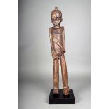 A Lobi standing male figure, Burkina Faso, with a crested coiffure and left arm across torso, 72.5cm