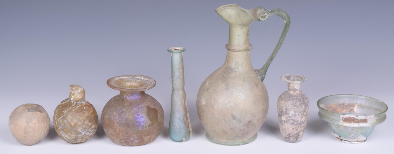 A Roman green glass jug, with a pinched spout and loop handle, 17cm high, a turquoise glass - Image 2 of 4