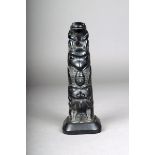 A Haida agrilite totem pole, carved a bear devouring a beaver, a eagle with a human head in its beak