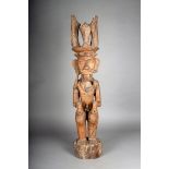 A Nias seated ancestor figure, Indonesia, with headdress, single earring and clenching two