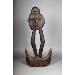 A Papua New Guinea suspension hook, carved with a mask, open supports on a twin hook base, 78cm