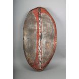 A Maasai hide shield, Kenya, of eliptical form, pigment decoration, wooden rib and handle, 97cm