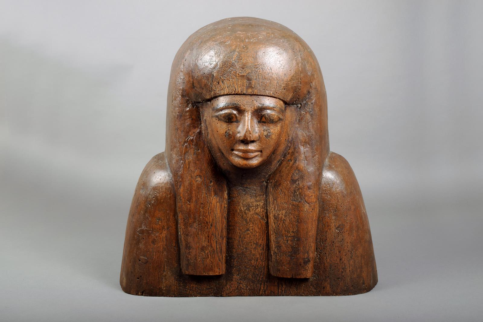 An Egyptian cedarwood mummy mask, carved a wig and with painted eyes and eyebrows, 18th-19th