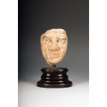 An Egyptian carved limestone head, with remains of polychrome decoration, 10cm high, possibly Old