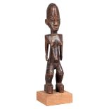 A Lobi standing female figure, Burkina Faso, with ovoid head, flat shoulders and straight arms