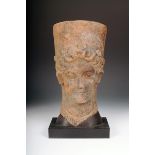 An Etruscan terracotta head of Demeter, with plaited hair and tall diadem with five discs, almond
