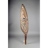 A Papuan Gulf gope board, carved with a mask with traces of white pigment, with a handle, the top
