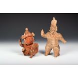 A Nayarit pottery figure of a ball player, seated and holding a shield and throwing a ball, 15.5cm