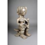 A Fante seated mother with suckling twins, Ghana, wood covered with silver coloured metal, on a