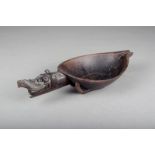 An Indonesian bowl, with a mythical beast handle and shallow spout, 31.5cm long.