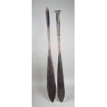 Two Northwest Coast cedarwood paddles, with leather string binding, one with grip missing, 148cm and