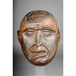 A Congo mask, with shallow coiffure and oval raised forehead tablet, pierced eyes and mouth, with