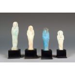 Four Egyptian faience shabtis; one turquoise with hieroglyphs to the reverse, 6.7cm, on wood stands.