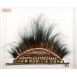 An Irian Jaya headdress, South Borneo, with fibre, shells, seeds and feathers, 60cm wide, in a