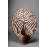 A Kikuyu shield, Kenya, almond shape with integral arm band, carved with jagged edge designs with