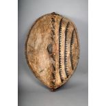 A Maasai hide shield, Kenya, with central boss and painted decoration, with wood rib/handle,