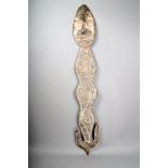 A Sepik suspension hook, Papua New Guinea, carved with a mask and stylised decoration, with twin