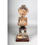 A Songye fetish figure, D.R. Congo, with pierced head with a ribbed rim, 40cm high, with a stand.