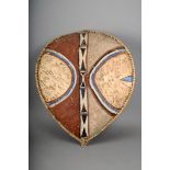 A Maasai hide shield, Kenya, with a central boss and painted decoration, with a wood rib/handle,