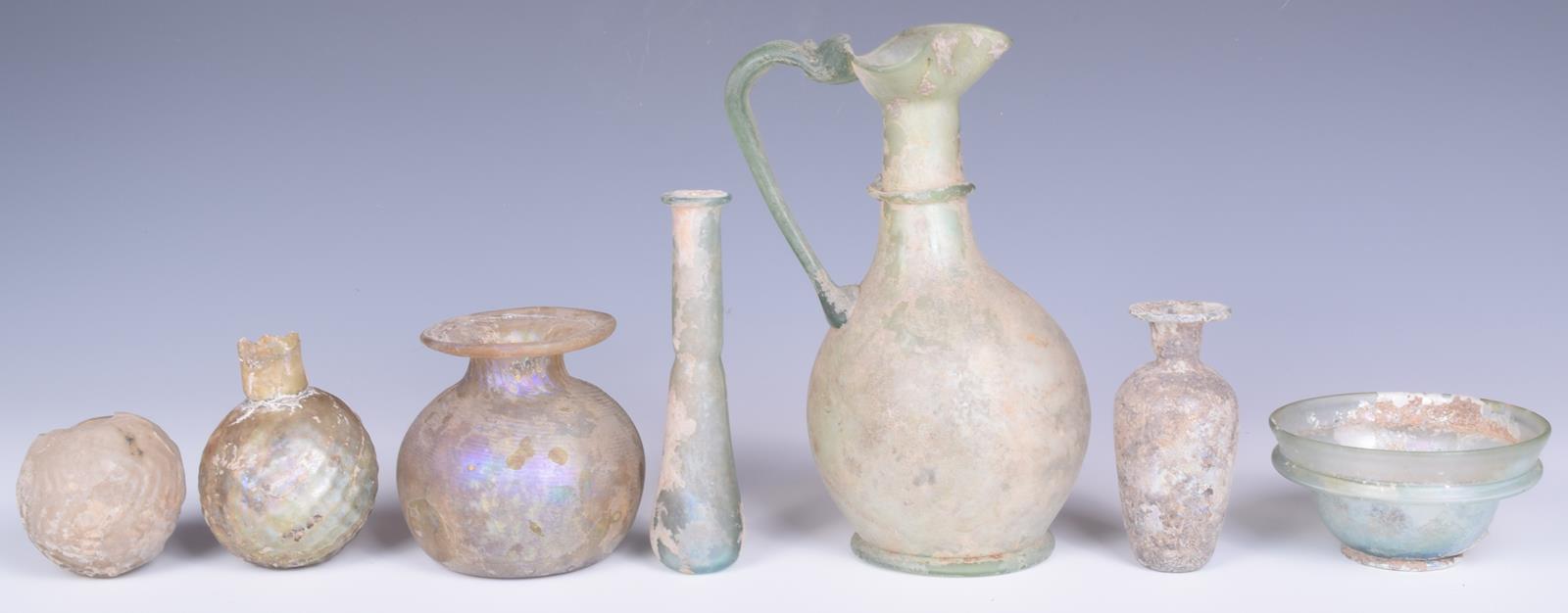 A Roman green glass jug, with a pinched spout and loop handle, 17cm high, a turquoise glass - Image 3 of 4