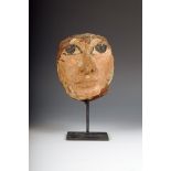 An Egyptian carved wood mask, with polychrome decoration, 13cm high, on a stand. (2)