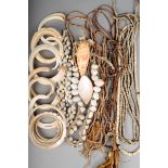 Four Oceanic shell bangles, the largest 9.7cm diameter, six hog tusks, a shell necklace on fibre,