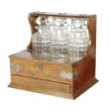 An Edwardian oak tantalus, with silver plated mounts, with a mirrored back and three glass decanters