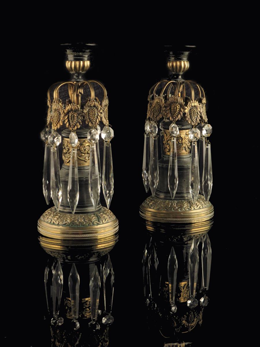 A pair of early 19th century gilt and patinated bronze candlesticks, each hung with cut glass